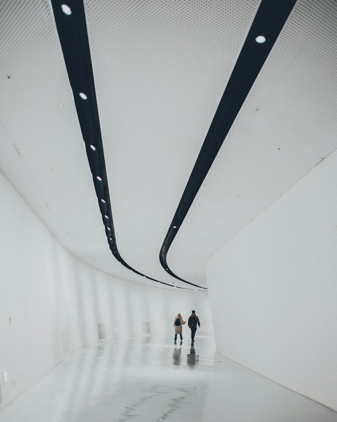 Young woman seen from behind walking through a minimalist museum corridor